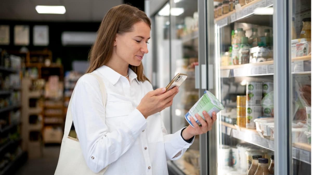 Eine Frau steht im Supermarkt vor einem Kühlregal