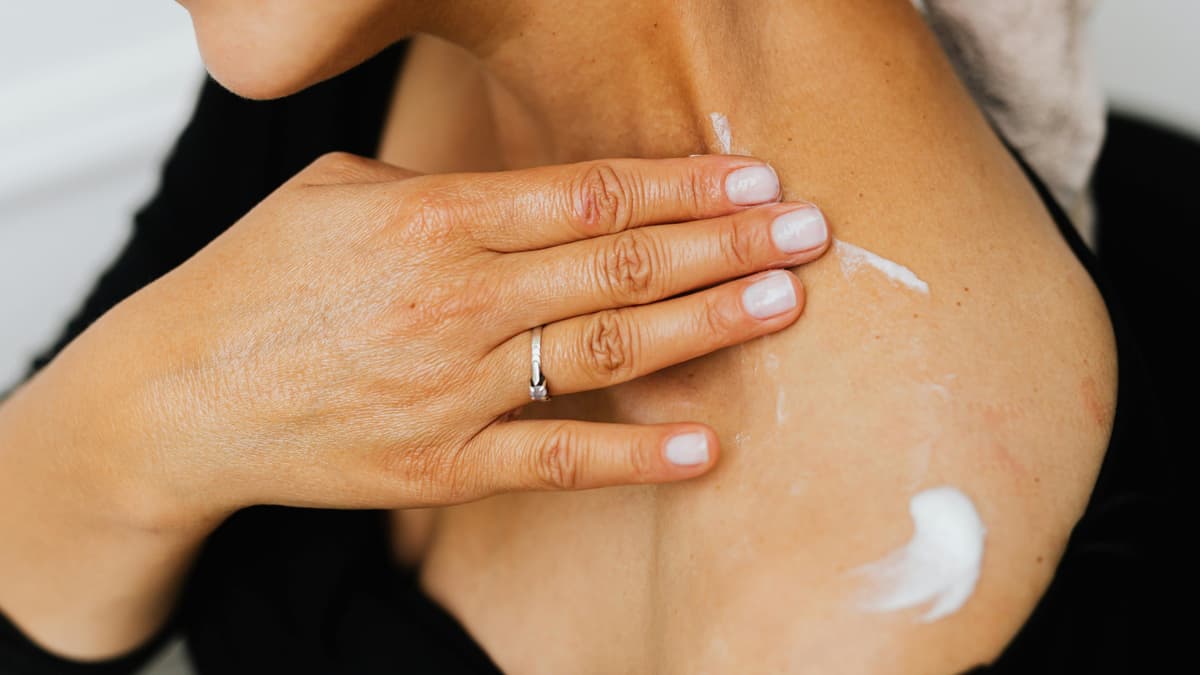 Frau cremt Schulter ein