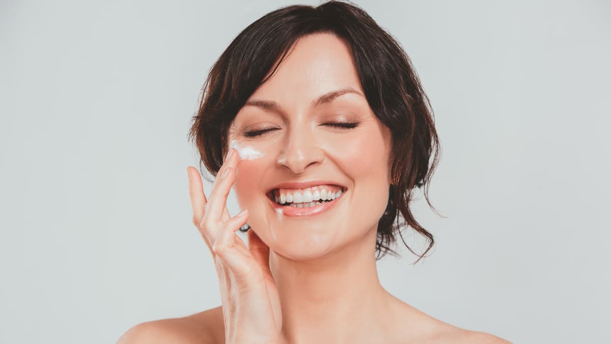 Frau trägt Gesichtscreme auf.