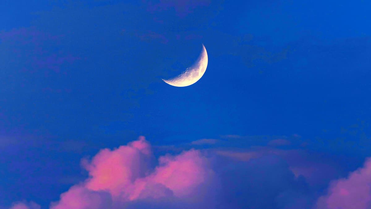 Sichelmond vor blauem Himmel und rosa Wolken