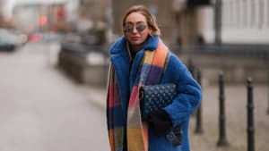 Streetstyle Frau trägt Jeans, blauen Mantel und bunt karierten Schal