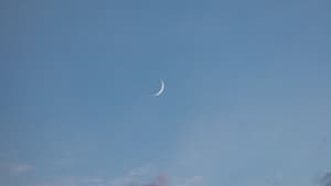 Neumond am Himmel mit rosafarbenen Wolken