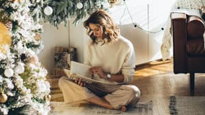 Frau liest ein Buch unter dem Weihnachtsbaum.