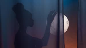 Frau mit Dutt hält den Vollmond in der Hand