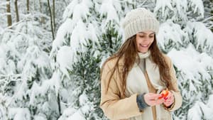 Lebensmittel im Winter: Frau im Winter isst eine Mandarine 