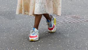 Frau trägt bunte Sneaker und ein Midikleid auf London Fashion Week
