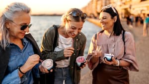Drei Frauen lachen essen ein Eis im Becher