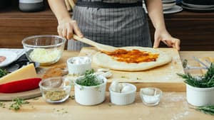 Frau belegt einen Pizzateig