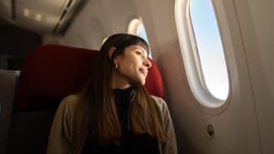 Frau sitzt im Flugzeug und guckt aus dem Fenster