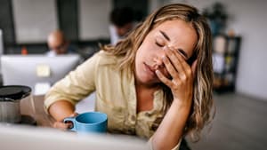 Frau sitzt müde am Tisch.