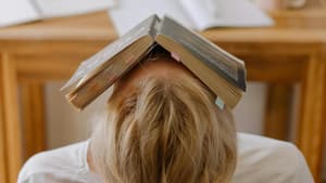 Gestresste Frau mit Buch auf dem Kopf
