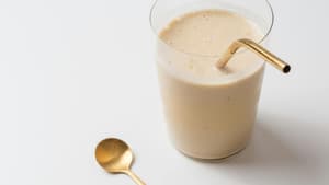Ein cremiger Shake im Glas mit goldenem Strohhalm.