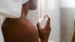 Frau sprüht nach dem Duschen Parfum auf.