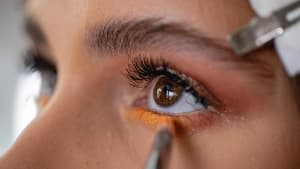 Frau trägt sich orangene Farbe unter den Augen auf.