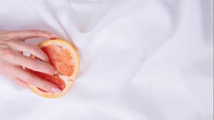 Zitrusfrucht liegt auf einem weißen Tuch und eine Hand fasst herein.