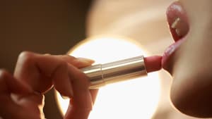 Frau trägt Lippenstift auf die Lippen auf.