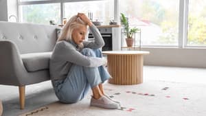 Frau sitzt traurig am Boden