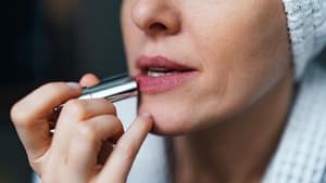 Frau trägt Lippenstift auf ihre Lippen auf.