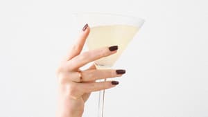 Frauenhand mit Nagellack hält Sektglas