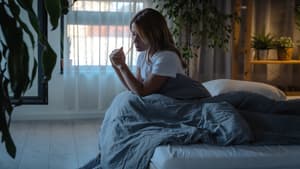 Frau sitzt traurig und allein im Bett