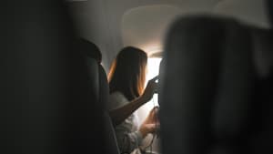 Frau sitzt im Flugzeug und guckt aus dem Fenster.