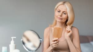Reife Frau bürstet Haare kritisch