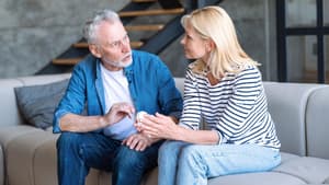 Mann und Frau sitzen auf einer hellen Coach und führen ein Gespräch.