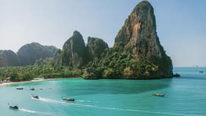 Die Küste von Krabi mit grünen Felsen und türkisblauem Meer und Booten.