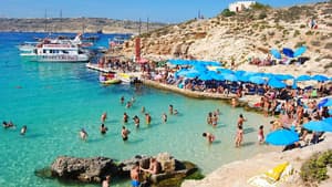 Viele Touristen am Strand im Wasser und unter Sonnenschirmen.