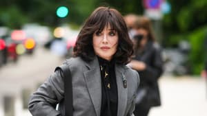 Frau mit dunklem Longbob und Pony trägt eine schwarze Bluse und einen grauen Blazer.