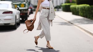 Frau mit rotem Lippenstift trägt ein weißes Top, eine beige Chinohose und Kitten Heals auf der Straße.