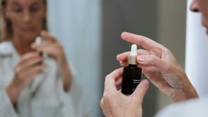 Frau hält Hautpflegeserum in der Hand.