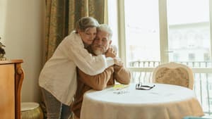 Eine Frau umarmt von hinten einen Mann und kuschelt sich an ihn.