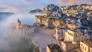 Ein Blick auf Matera mit vielen beigefarbenen Häusern und Nebel drum herum.