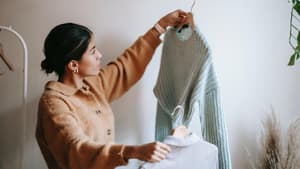 Eine junge Frau sortiert Kleidung aus