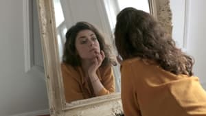 Eine Frau betrachtet sich im Spiegel