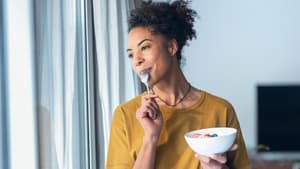 Eine Frau isst einen Joghurt mit Früchten