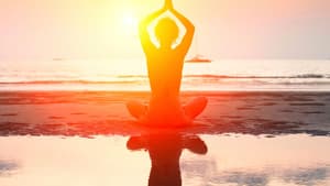 Frau macht Yoga am Strand.