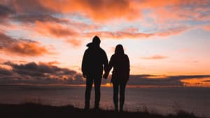 Frau und Mann von hinten schauen sich den Sonnenuntergang an.