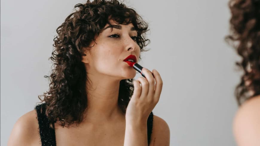 Frau trägt roten Lippenstift auf.