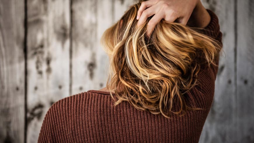 Frau fasst sich in die Haare