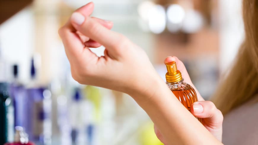 Frau mit Parfum in der Hand