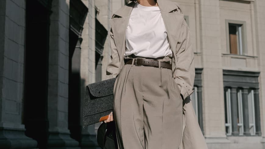 Frau trägt Trenchcoat, weite Hose und weißes T-Shirt