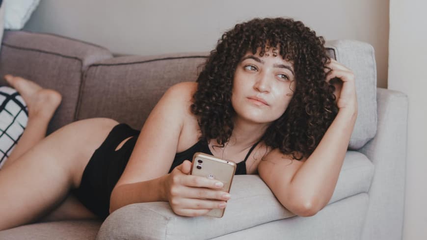 Frau mit Handy auf Sofa 