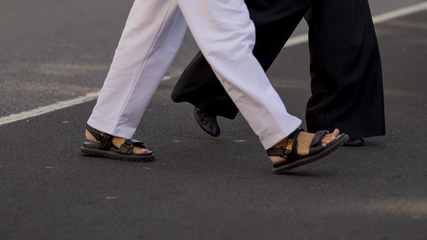 Frau mit weißen Hosenanzug und flachen Sandalen