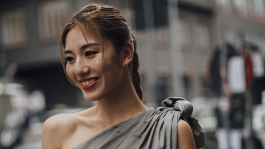 Mailand Fashion Week Frau trägt Kleid und Zopf lächelt