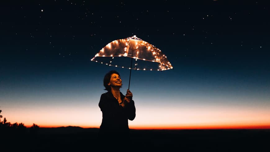 Frau in der Nacht mit leuchtendem Regenschirm
