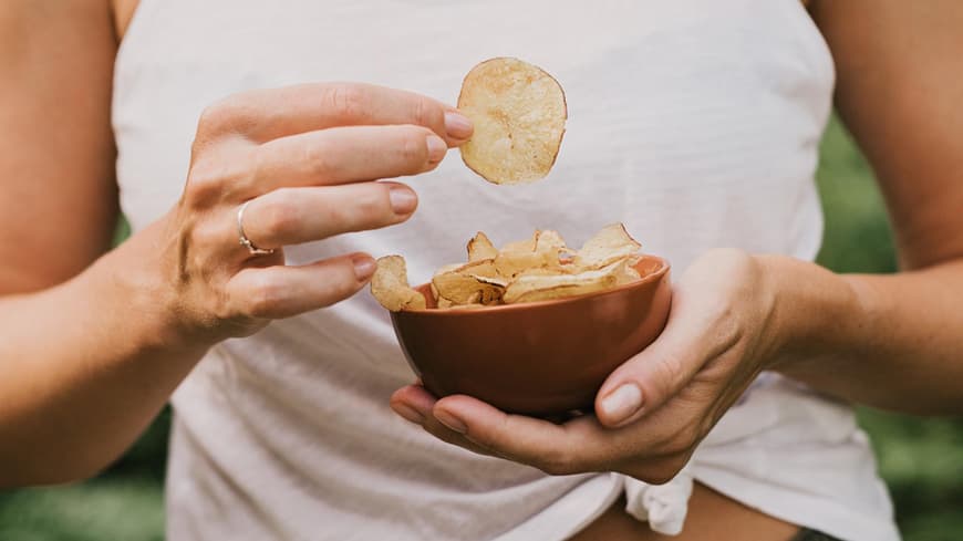 Frau isst Kartoffelchips