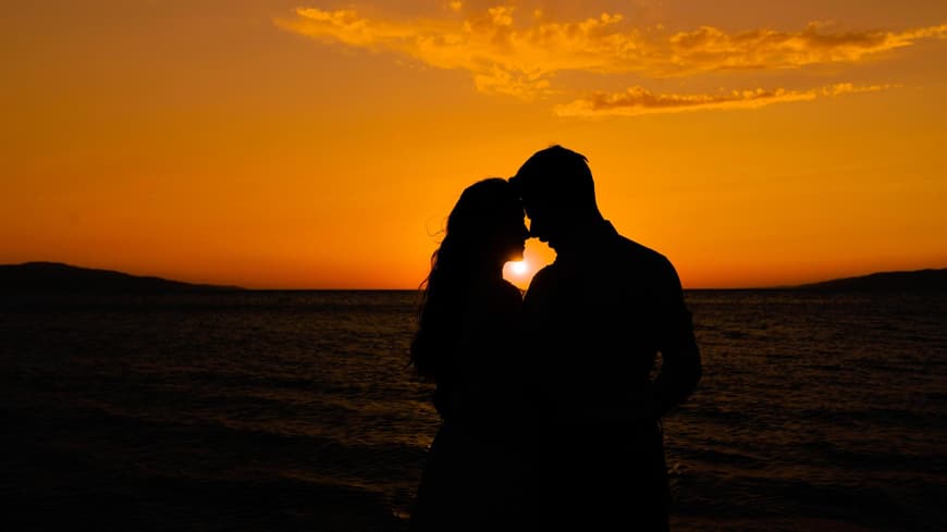Mann und Frau stehen verliebt vor dem Sonnenuntergang