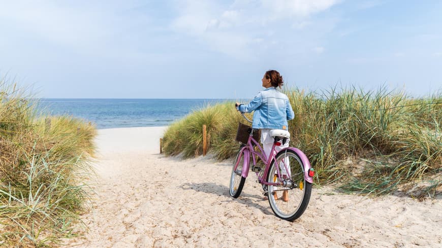 Frau auf Fahhrad an einem Strand in Ostdeutschland